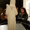 Sala di un museo: una statua di spalle, due studentesse la osservano di fronte
